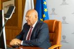 Minister Tadeusz Kościński siedzący przy biurku przed monitorem komputera.