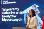 Minister Magda Rzeczkowska przemawia podczas konferencji. W tle napis Wspieramy Polaków w spłacie kredytów hipotecznych.