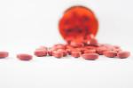 rozsypane czerwone tabletki - w tle jedna większa